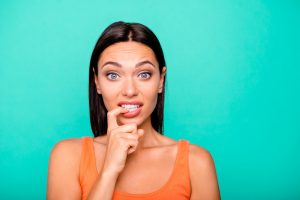 Close up photo portrait of depressed negative expressing nervous girl biting nails damaging new manicure isolated pastel background.