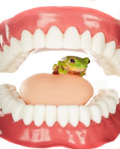 mouth open with a frog sitting inside of the mouth on the tongue