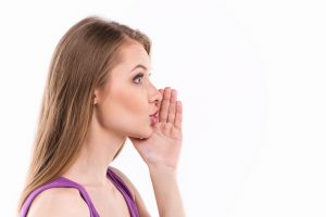 Young woman whispering over white background. profile of beautiful girl whispering message