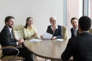 Multi ethnic hr managers laugh at funny joke of male applicant at job interview, diverse recruiters employers having fun talking to candidate make good first impression, hiring recruiting concept