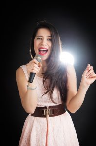 Female singer sings into a microphone on a black background