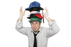 Businessman wearing several different hats stacked on top of each other