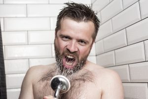 Man singing in the shower, using the shower head as a microphone