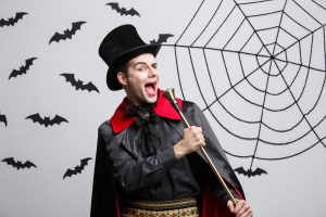 Man wearing a magician costume speaking into a cane 