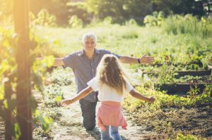 I need your hug. Granddaughter running in hug to her grandfather. Copy space. Focus on senior man.