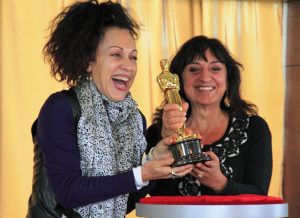 Two women smiling while holding and Oscar award