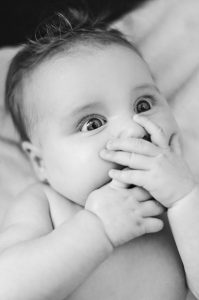 A baby with hands over its mouth 