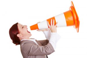 Angry business woman shouting in a big traffic cone