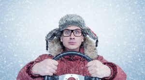 Man in the middle of a blizzard holding a steering wheel