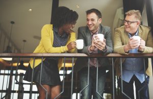 Business people gathering in discussion and small talk with coffee in hand