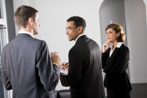 Diverse businesspeople conversing and taking notes, focus on African American man in middle