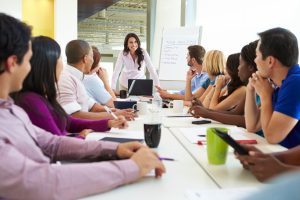 Businesswoman Addressing Meeting Around Boardroom Table