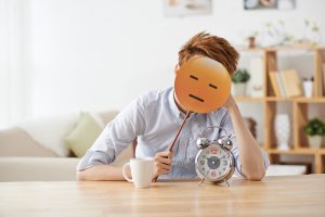 Man sitting at the table with a non-amused emoji over his face