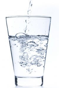 glass of clear water with water being poured into it