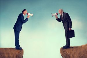 Two men standing on opposing ledges having a discussion with megaphones