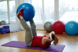 Woman working out on a yoga mat with medicine balls 