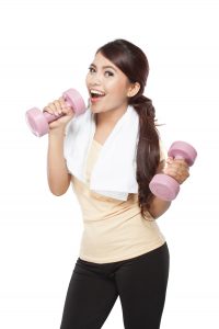 A portrait of an Asian woman exercising, holding barbell, isolated over white background