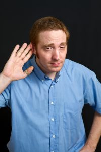 Man with his hand pushing his ear forward to be able to hear better