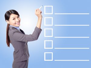 Beautiful business woman Filling Check list in the air (empty copy space great for your design) with blue background, asian model