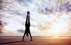 Handstand yoga pose by man silhouette on the beach near the ocean in India