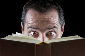 Man with eyes wide open while reading a book