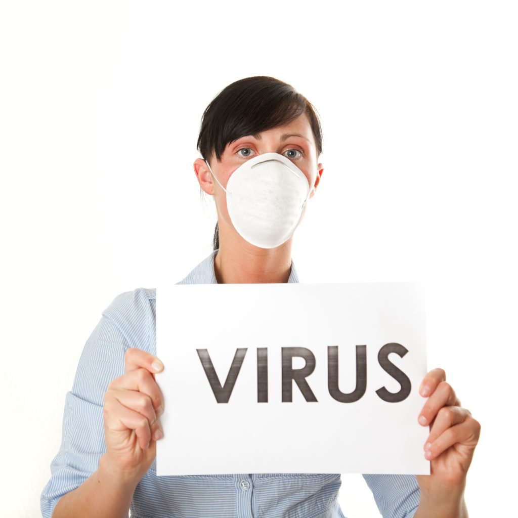Woman with a medical mask holding up a sign that says virus