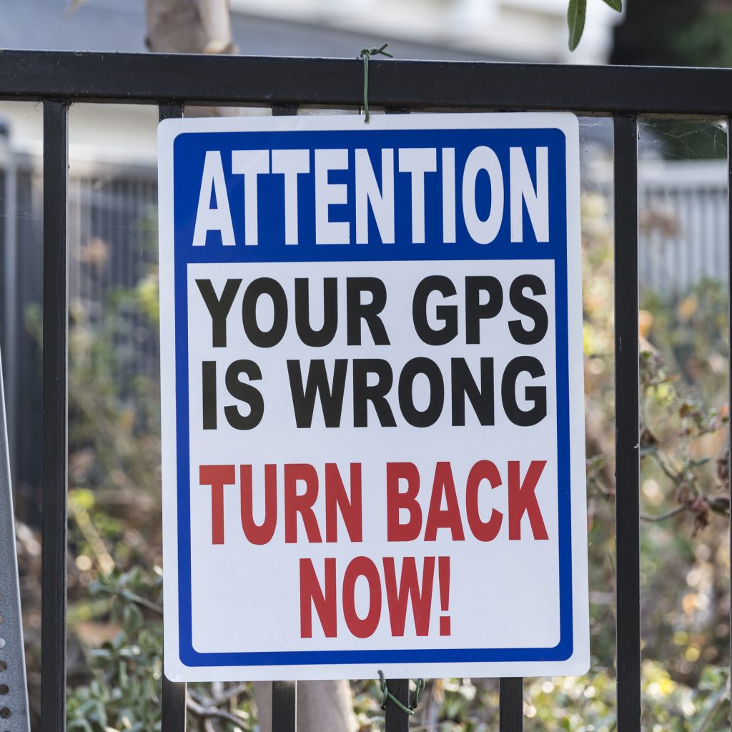 A warning sign that says "attention your GPS is wrong turn back now"