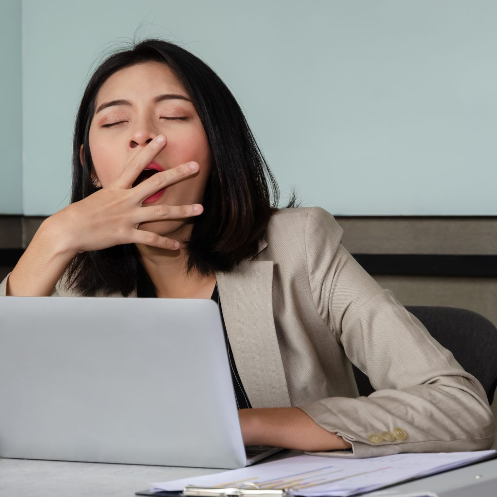 Businesswoman sitting at the computer and yawning.