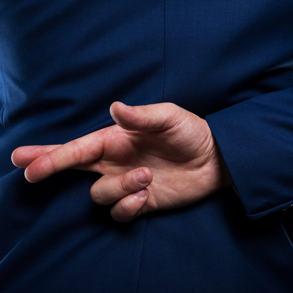 Business person with they fingers crossed behind their back
