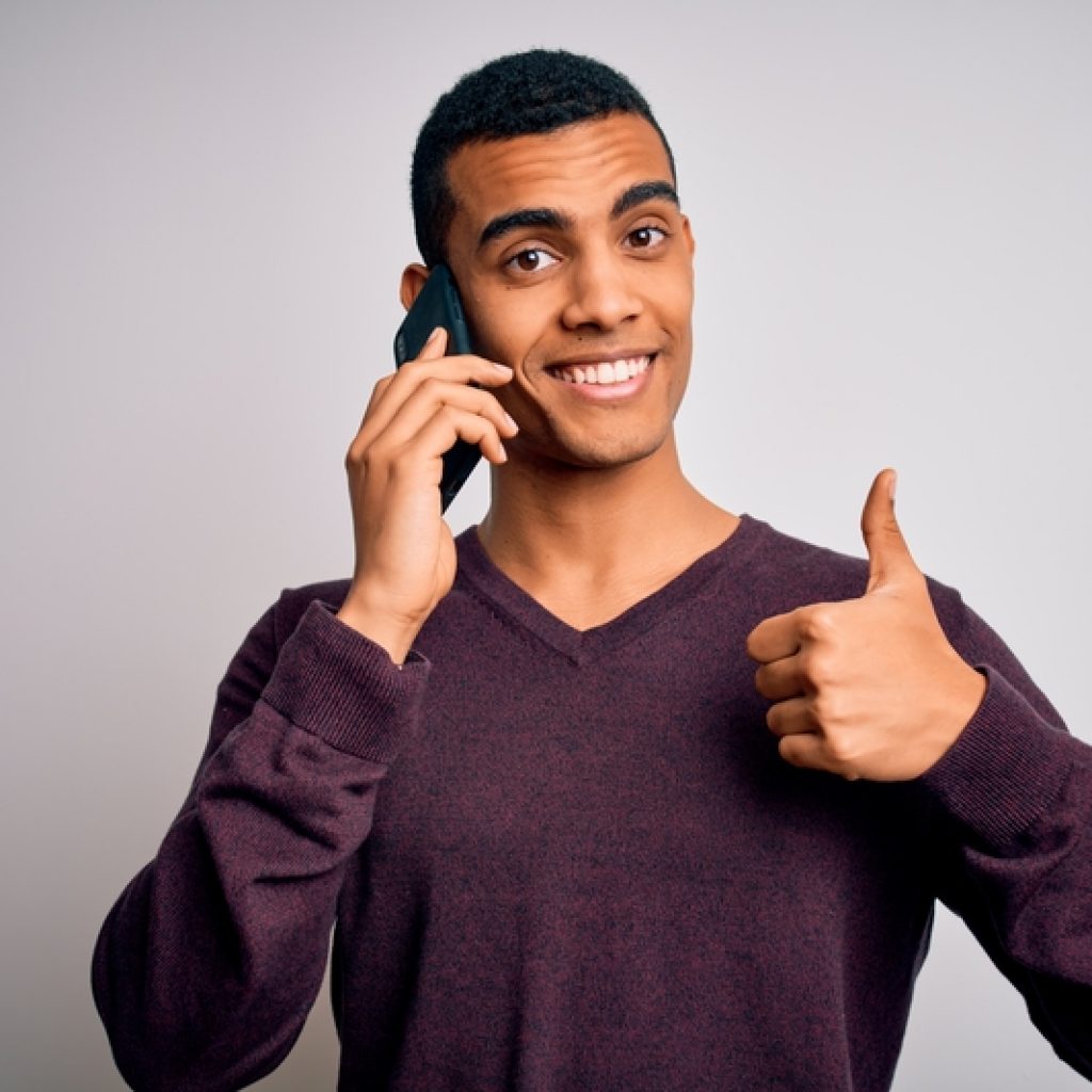 Businessman having a conversation on the phone with a big smile on his face and a thumbs up
