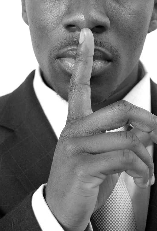 Business man with his finger over his mouth signaling "shhhhh" (silence)